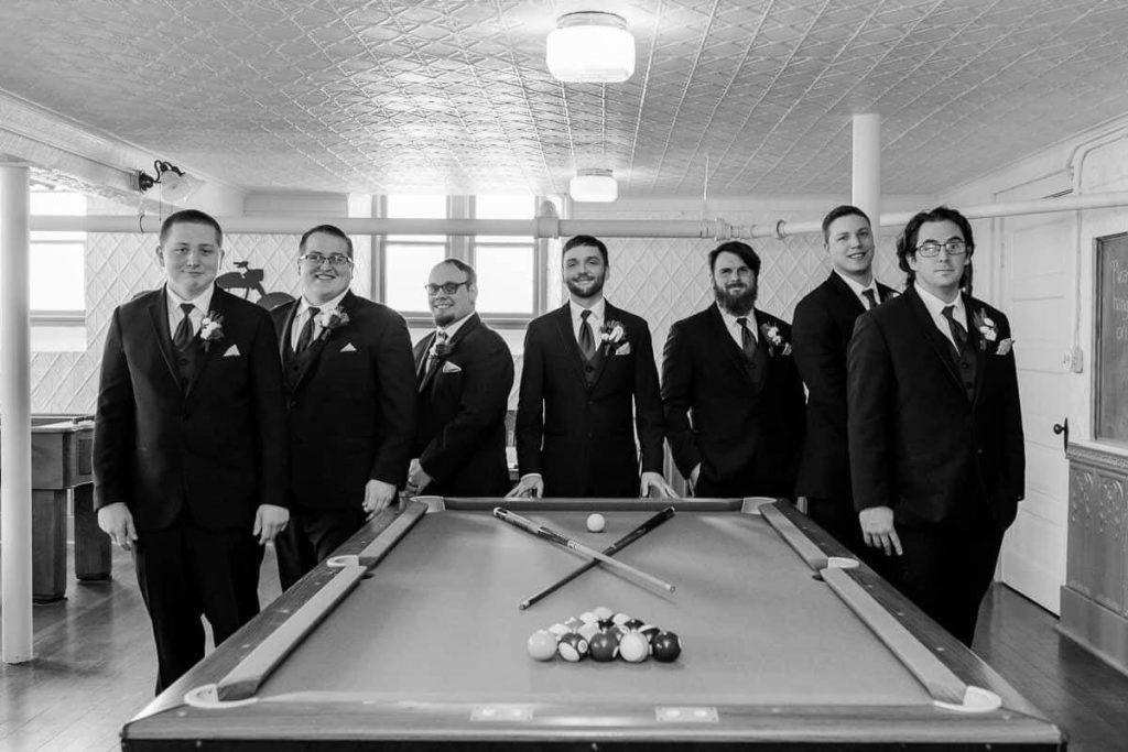 men standing around pool table