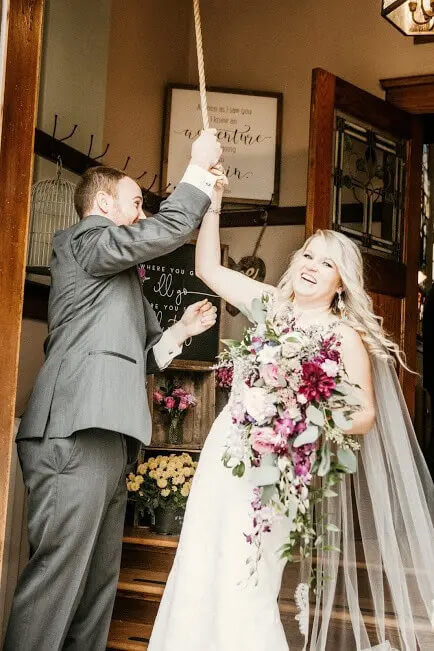 A bride and groom ringing the historic bell at Devotions Wedding Chapel