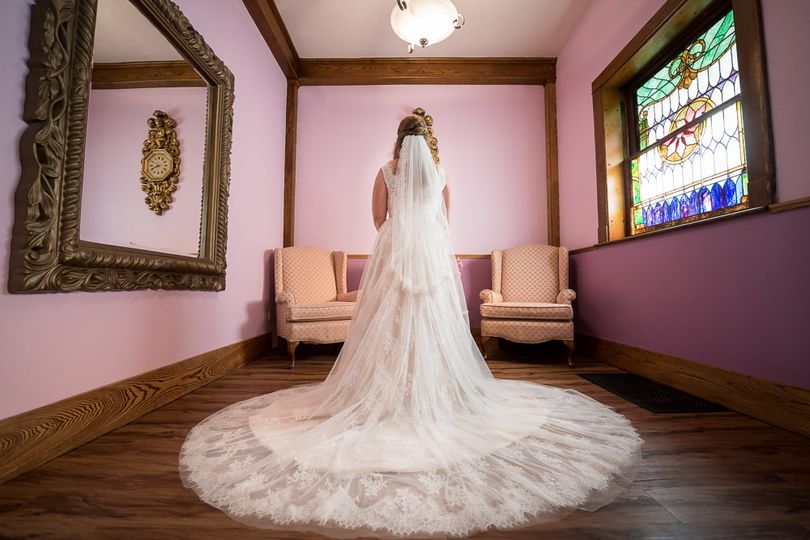 A bride posing in her wedding dress facing away from the camera in the bridal suite of a Green Bay wedding venue