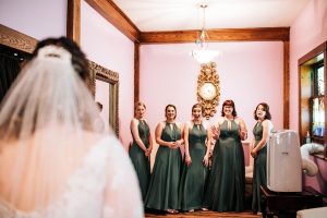 A bride surprises her bridesmaids with her wedding dress in the bridal suite prior to the wedding