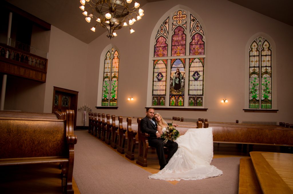 A newly-wed couple posing together in the front pew of Green Bay wedding venue